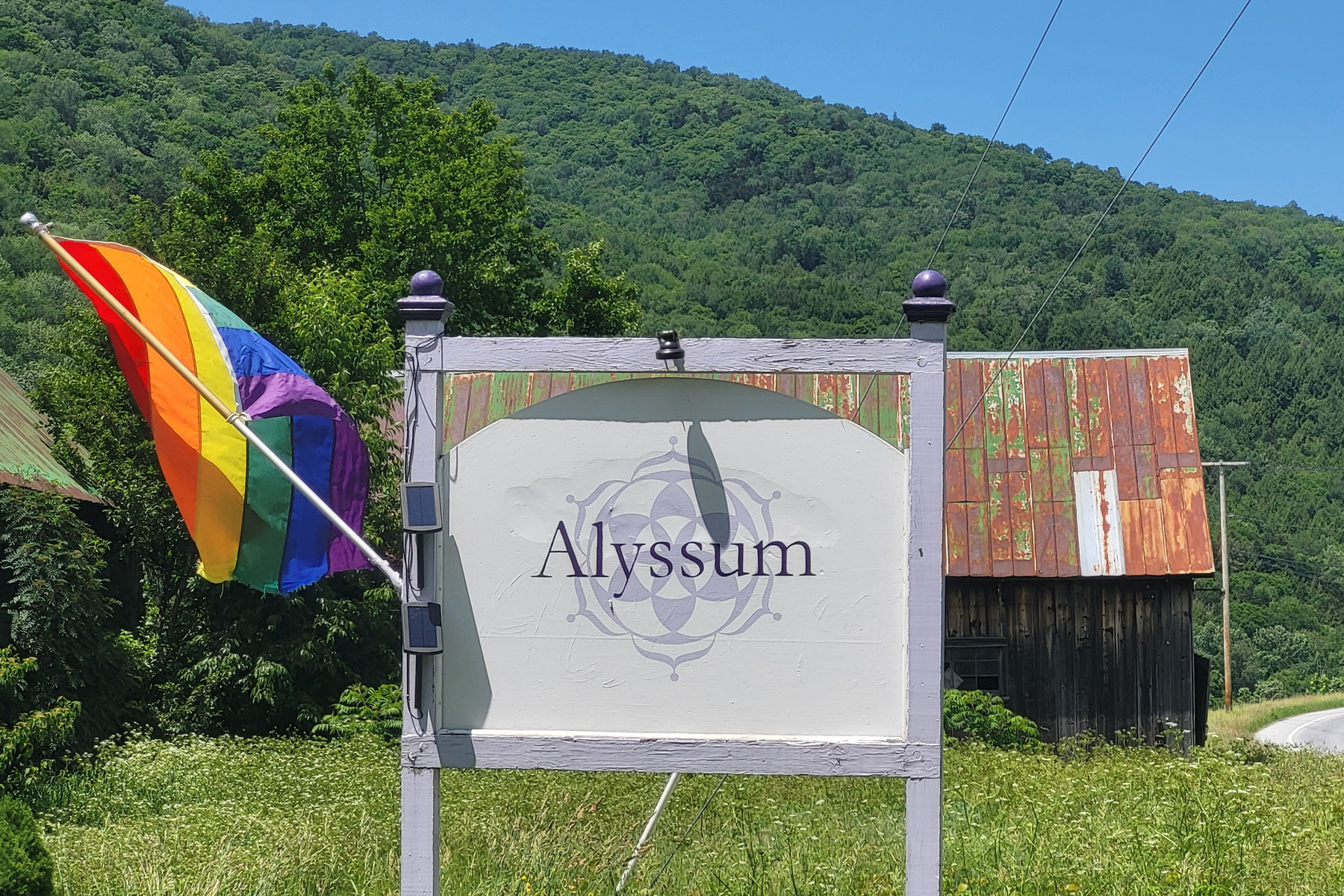 outdoor sign with rainbow flag by driveway